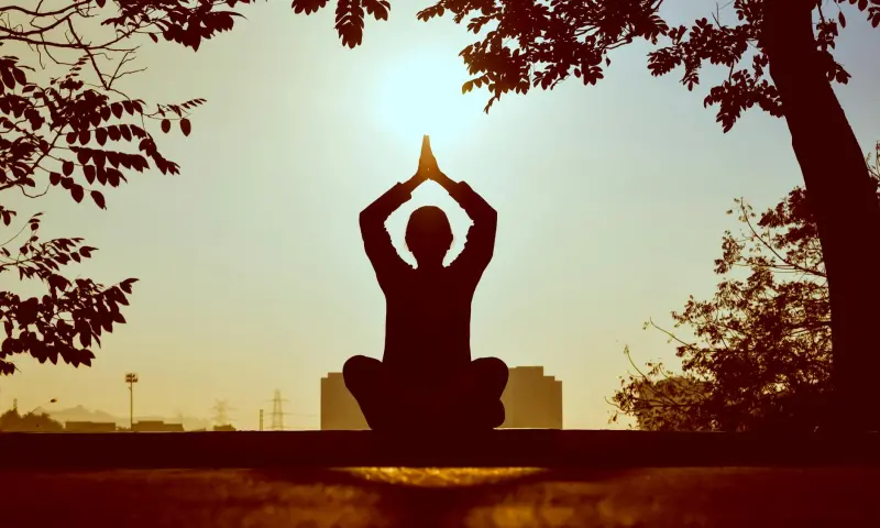Gün doğumunda yoga yapan kişi siluet — sakin başlangıç