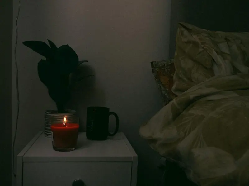 Sakin bir gece komidini — mum, fincan ve bitki — karanlık dinlenme ortamı