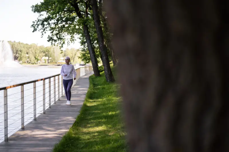 Yaşlı kadın sahil promenadında yürüyüş yapıyor — düzenli egzersiz