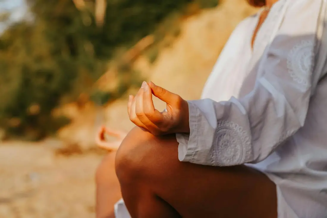 Gün batımında sahilde meditasyon yapan kişi — stresle başa çıkma